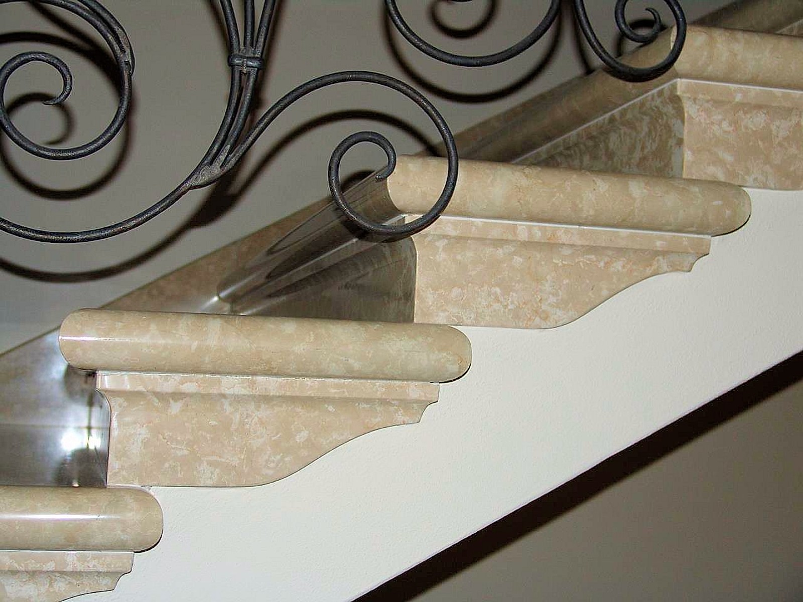 Scala rivestita in travertino con ringhiera in ferro battuto
